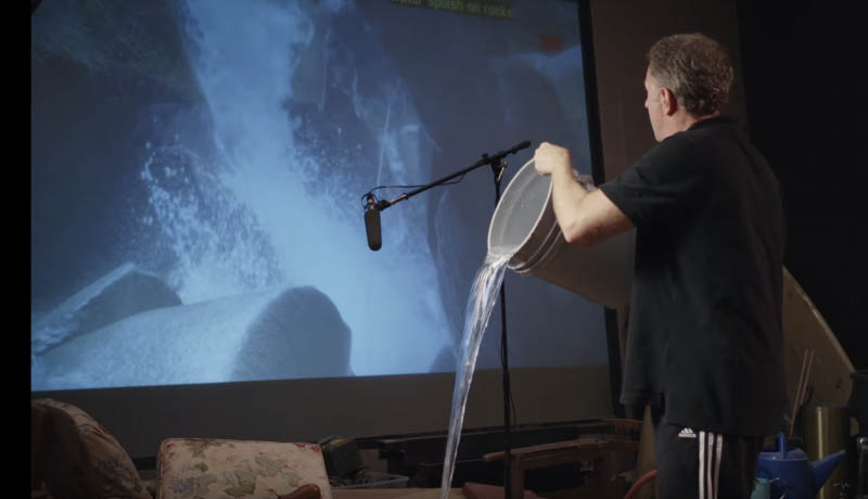 A foley artist pours water in sync with a visual on the screen.